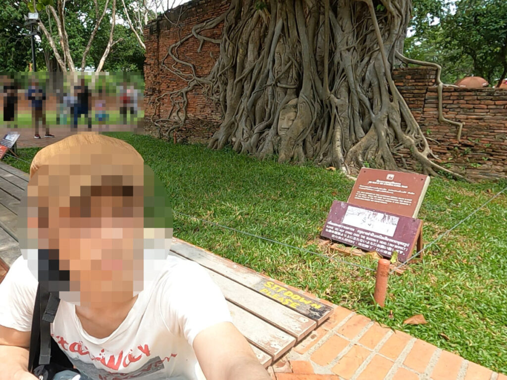 ワット・プラ・マハタートの樹木に覆われた仏像の頭と自撮りで記念撮影
